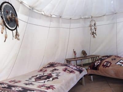 Tente tipi cosy avec lits décorés de motifs ethniques en Auvergne-Rhône-Alpes.