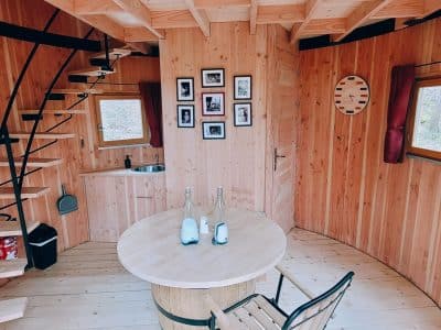 Cabane en bois ronde avec un intérieur chaleureux et une spirale descalier.