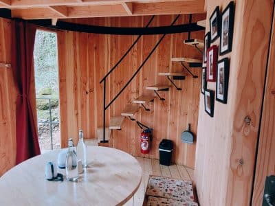 Cabane en bois avec un escalier en colimaçon et une vue sur la nature environnante.
