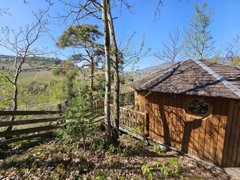 Cabane en bois avec fenêtre ronde, nichée dans la nature en Auvergne-Rhône-Alpes.