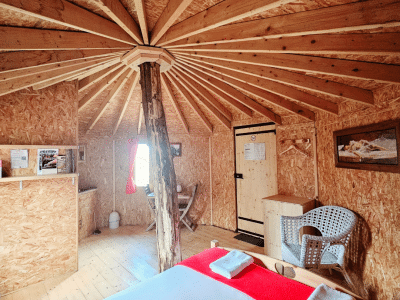 Cabane en bois avec un plafond en bois lamellé-collé et un lit confortable.