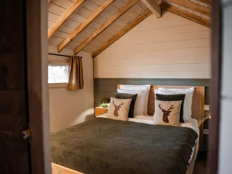 Chalet cosy avec lit douillet, décoré de coussins en forme de cerf.