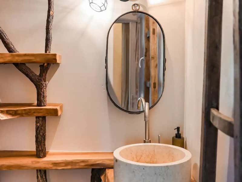 Salle de bain dun chalet, avec un lavabo en marbre et des étagères en bois naturel.