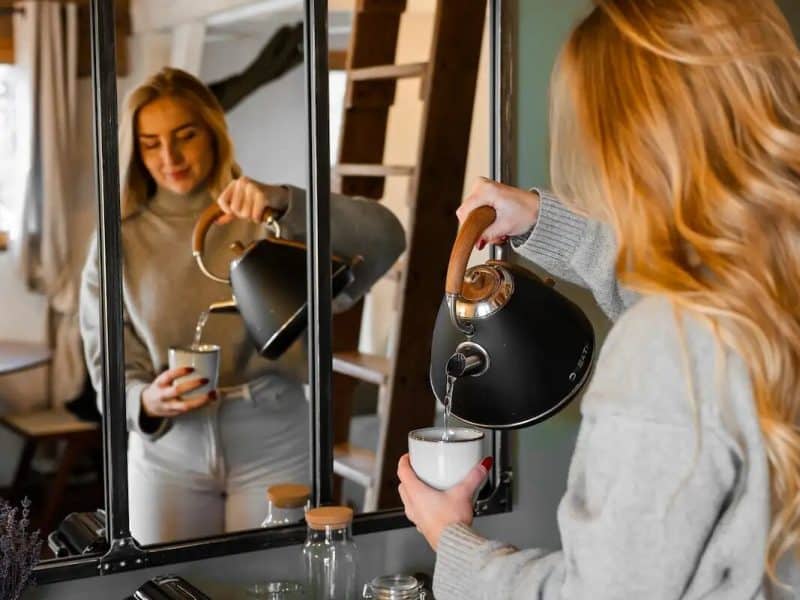 Chalet moderne avec une femme versant du thé devant un miroir élégant.