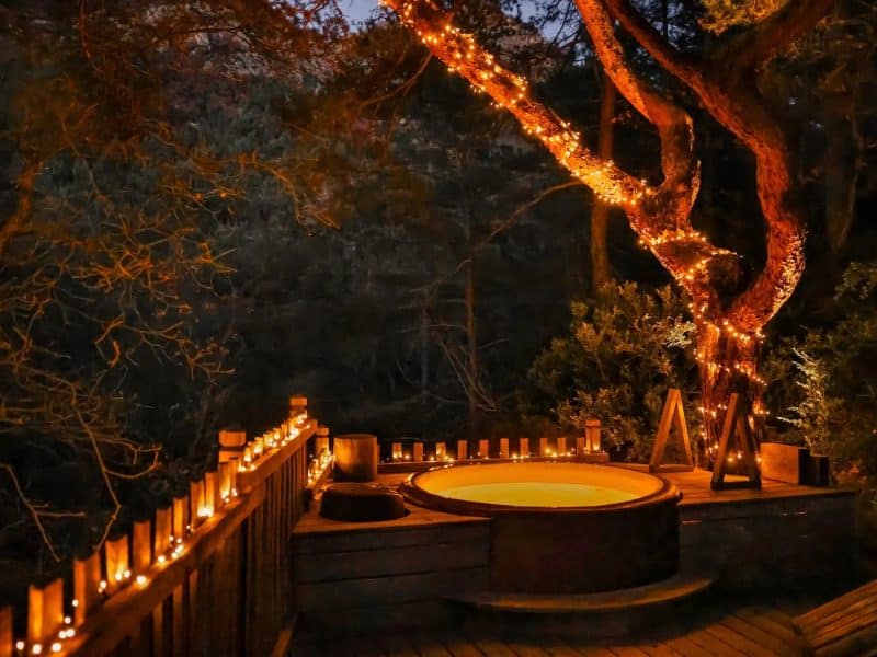 Hébergement romantique avec jacuzzi extérieur, illuminé par des guirlandes lumineuses.