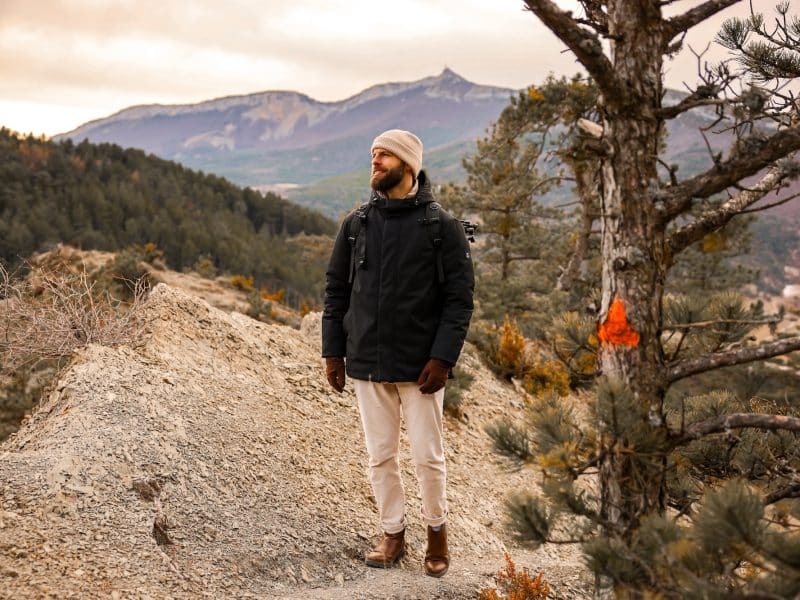 Hébergement en pleine nature, homme en randonnée avec montagnes en arrière-plan.
