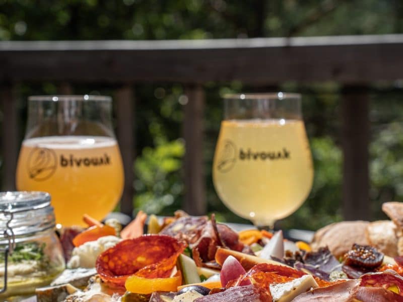 Planche apéritive gourmande avec bières artisanales, en terrasse dun hébergement chaleureux.