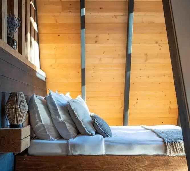 Chambre dhôtes moderne avec murs en bois et lit douillet, ambiance chaleureuse.