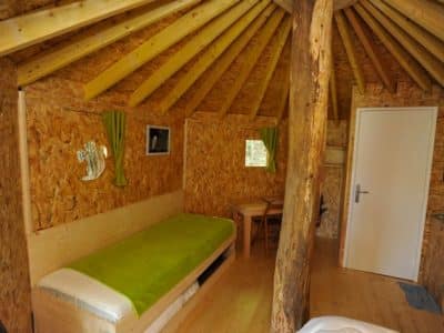 Yourte en bois avec intérieur chaleureux, lit simple et décoration naturelle.