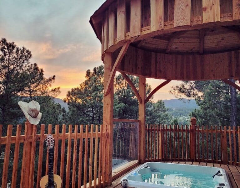 Cabane en bois avec jacuzzi, vue sur la nature au coucher de soleil.