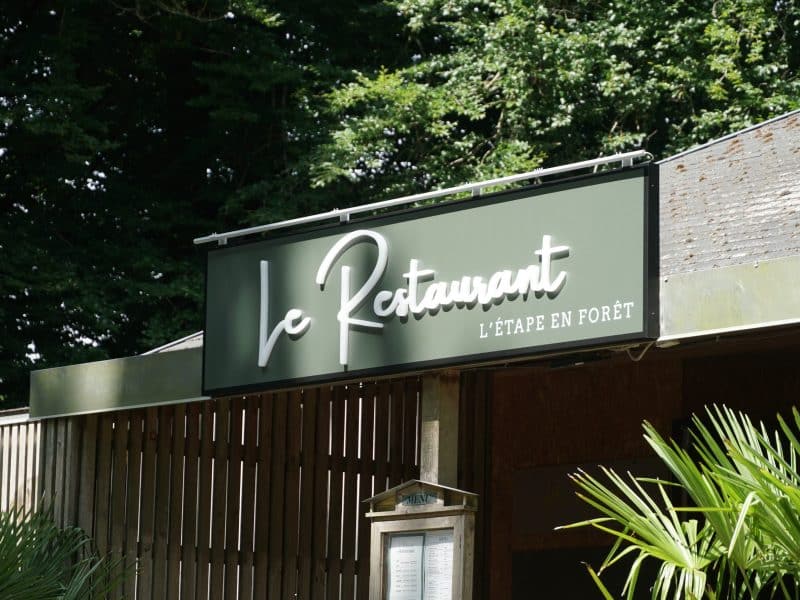 Restaurant LÉtape en Forêt avec une belle enseigne en bois et verdure environnante.