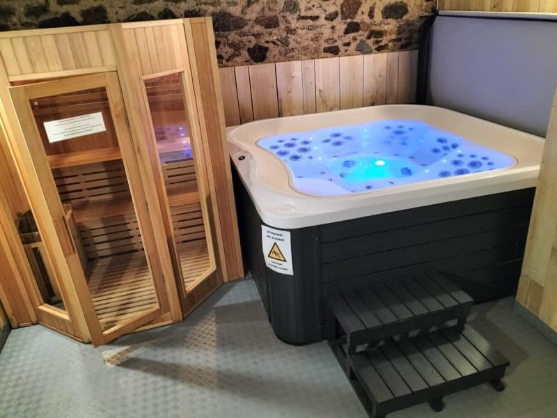 Hébergement de luxe avec jacuzzi lumineux et sauna en bois chaleureux.