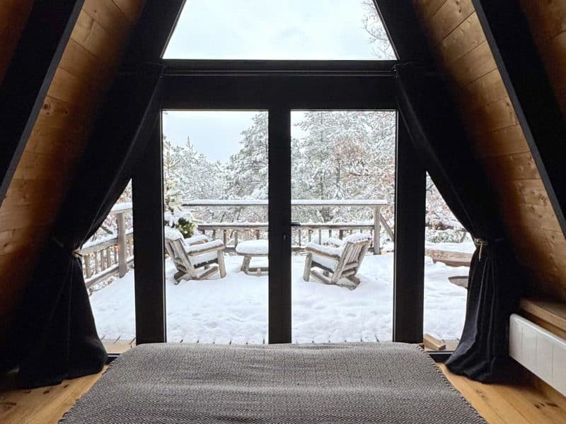 Chalet en bois avec vue sur la neige et terrasse en bois, ambiance chaleureuse.