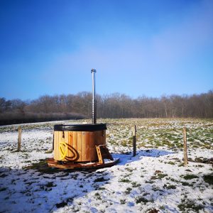 Hébergement insolite : un sauna en bois au milieu dun champ enneigé sous un ciel bleu.