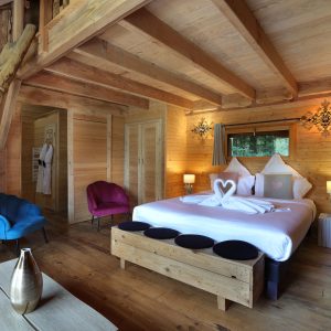 Chalet en bois chaleureux avec lit king-size et fauteuils colorés.