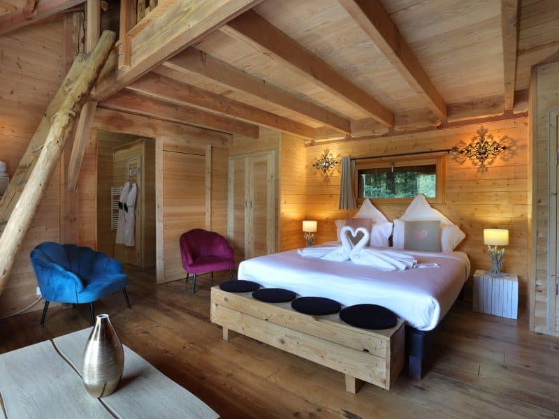 Chalet en bois chaleureux avec lit king-size et fauteuils colorés.