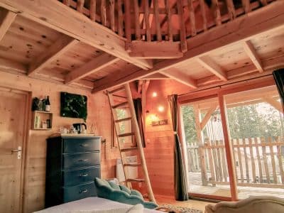 Cabane en bois avec mezzanine, ambiance chaleureuse et vue sur la nature.