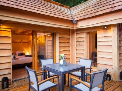 Cabane en bois avec terrasse, mobilier moderne et vue sur la nature en Auvergne-Rhône-Alpes.