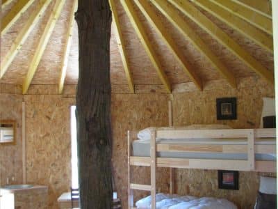 Intérieur dune yourte en Auvergne, avec un plafond en bois et lits superposés.