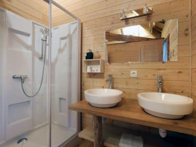 Salle de bain en bois dun chalet insolite en Auvergne-Rhône-Alpes, avec douche moderne.