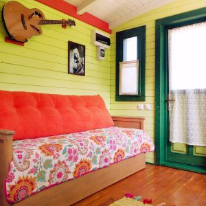 Chalet coloré avec un canapé fleuri et une guitare accrochée au mur.
