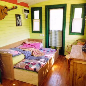 Chalet coloré avec lit douillet, décoré de bois et touches artistiques.