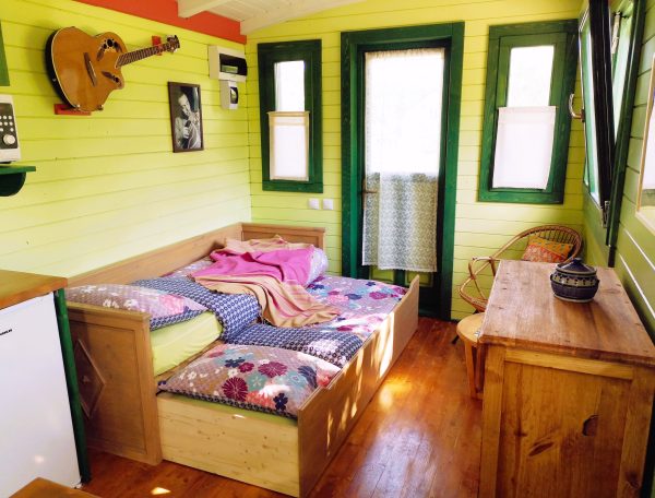 Chalet coloré avec lit douillet, décoré de bois et touches artistiques.