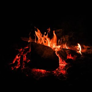Un chalet en bois avec un feu de camp crépitant dans la nuit étoilée.