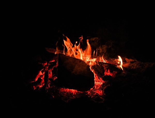 Un chalet en bois avec un feu de camp crépitant dans la nuit étoilée.