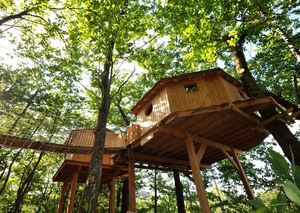 Cabane dans les arbres en bois, perchée parmi les feuillages verdoyants.