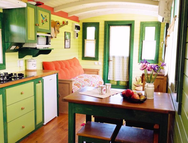 Charmante roulotte colorée avec cuisine équipée et coin repas accueillant.
