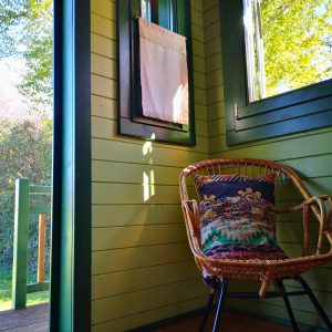 Cabane en bois à Bourgogne, avec une chaise en rotin et lumière naturelle.