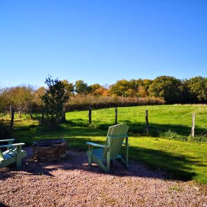 Hébergement insolite en Bourgogne avec chaises vertes et vue sur un champ verdoyant.