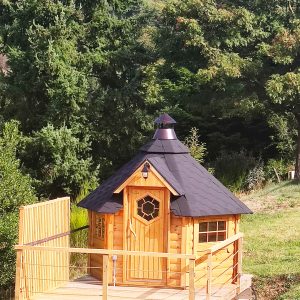 Cabane en bois avec terrasse, nichée dans un écrin de verdure.
