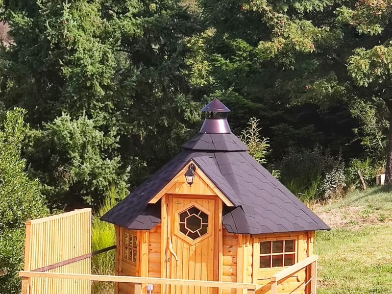 Cabane en bois avec terrasse, nichée dans un écrin de verdure.