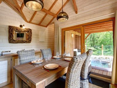 Chalet en bois en Bretagne avec un coin repas et un jacuzzi extérieur.