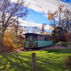 Hébergement insolite en Bourgogne : roulotte entourée darbres aux couleurs dautomne.