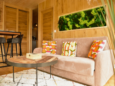 Hébergement insolite en Bretagne : chalet en bois avec un salon chaleureux et des coussins colorés.