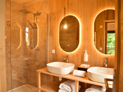 Salle de bain moderne en bois avec deux vasques dans un hébergement insolite en Bretagne.
