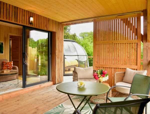 Cabane en bois avec terrasse, vue sur la nature et mobilier confortable.