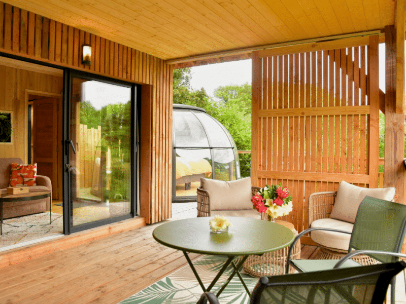 Cabane en bois avec terrasse, vue sur la nature et mobilier confortable.