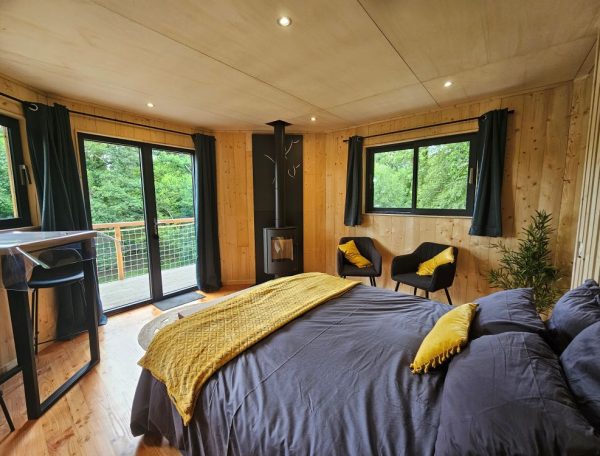 Chalet moderne avec lit douillet et vue sur la nature, ambiance chaleureuse.