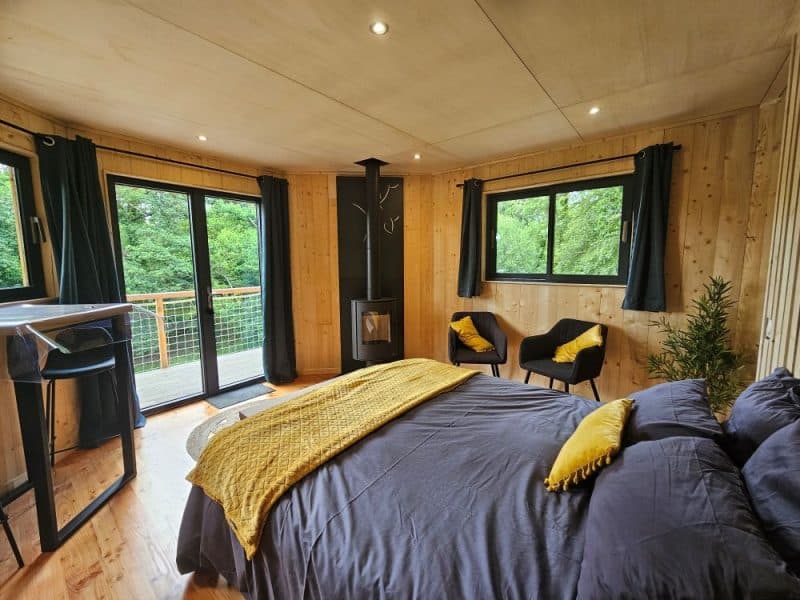 Chalet moderne avec lit douillet et vue sur la nature, ambiance chaleureuse.
