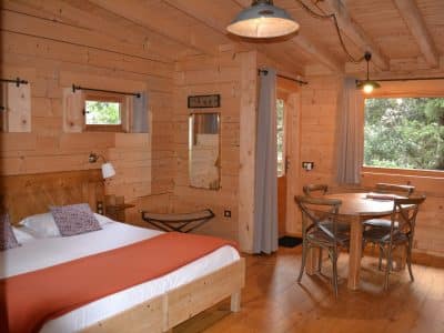Chalet en bois chaleureux avec lit double et coin repas lumineux.