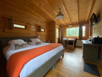 Chalet en bois chaleureux avec lit double et vue sur la nature environnante.