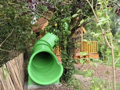 Hébergement insolite en Hauts-de-France avec toboggan vert et cabane en bois.
