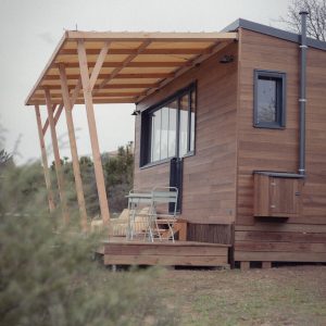 Cabane en bois avec terrasse, idéale pour un séjour en pleine nature.