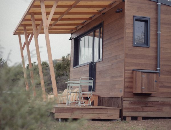 Cabane en bois avec terrasse, idéale pour un séjour en pleine nature.