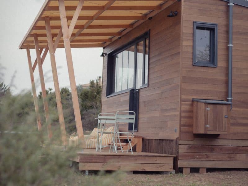 Cabane en bois avec terrasse, idéale pour un séjour en pleine nature.