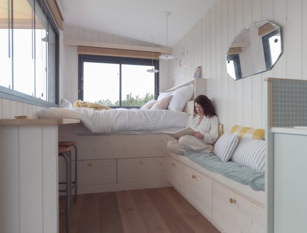 Chalet moderne avec lit confortable et vue panoramique, ambiance chaleureuse et lumineuse.